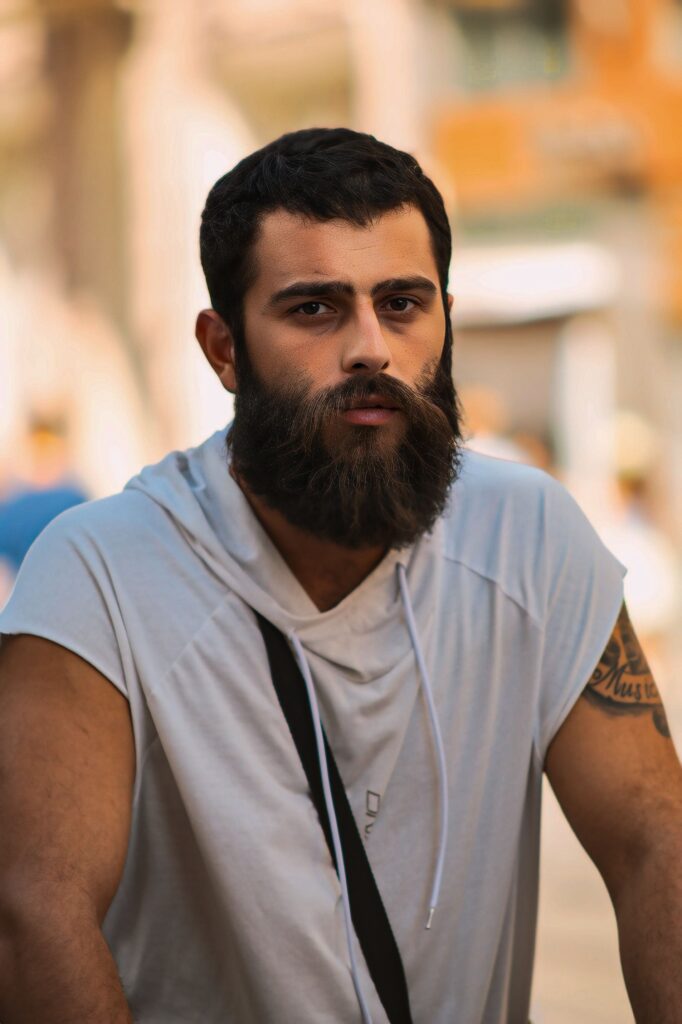 Portrait of a confident bearded man in casual urban fashion, posing confidently outdoors.